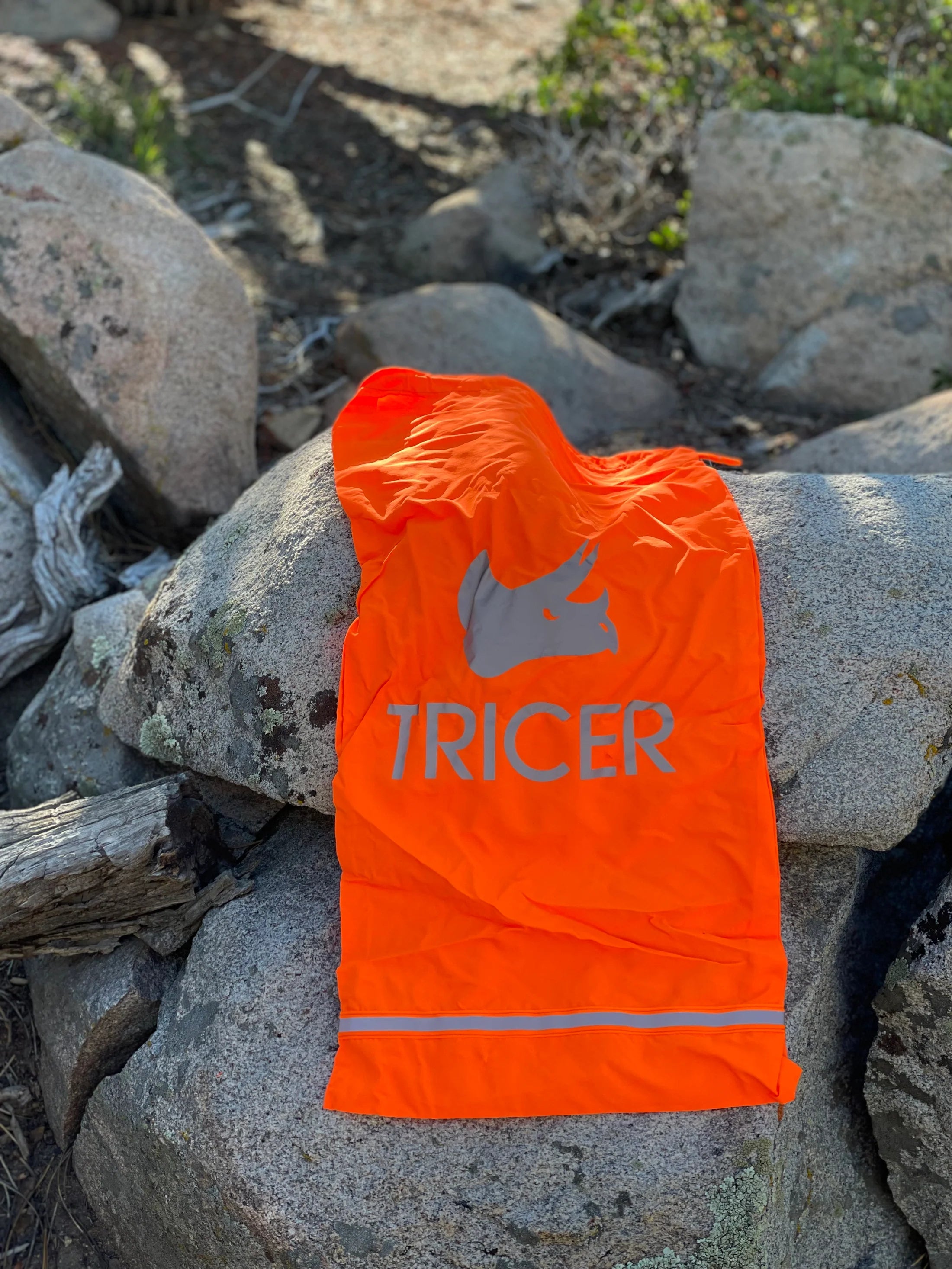 Orange game bag with 'TRICER' branding on a rocky background