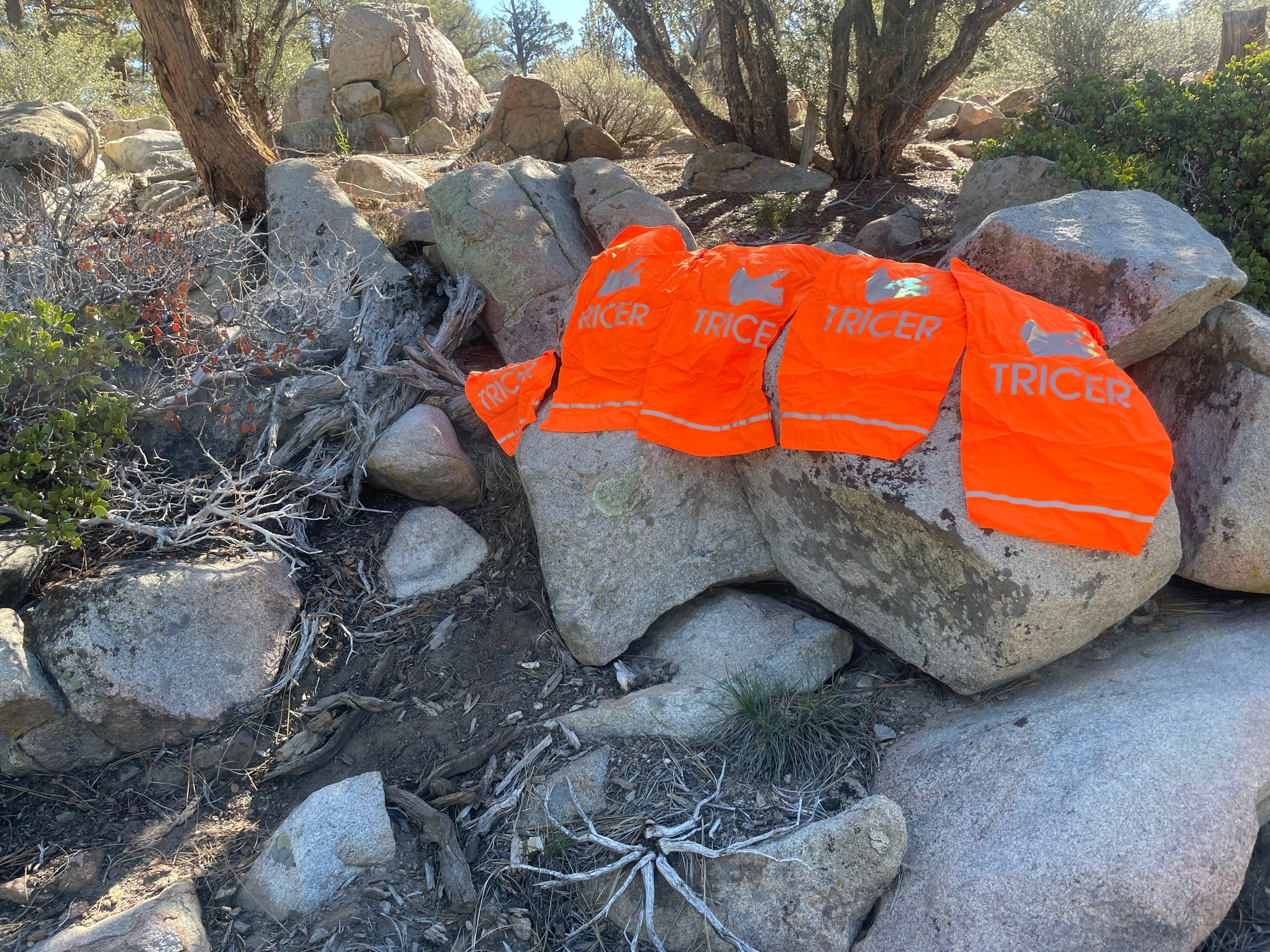Four orange game bags with 'Tricer' branding on a rocky terrain.