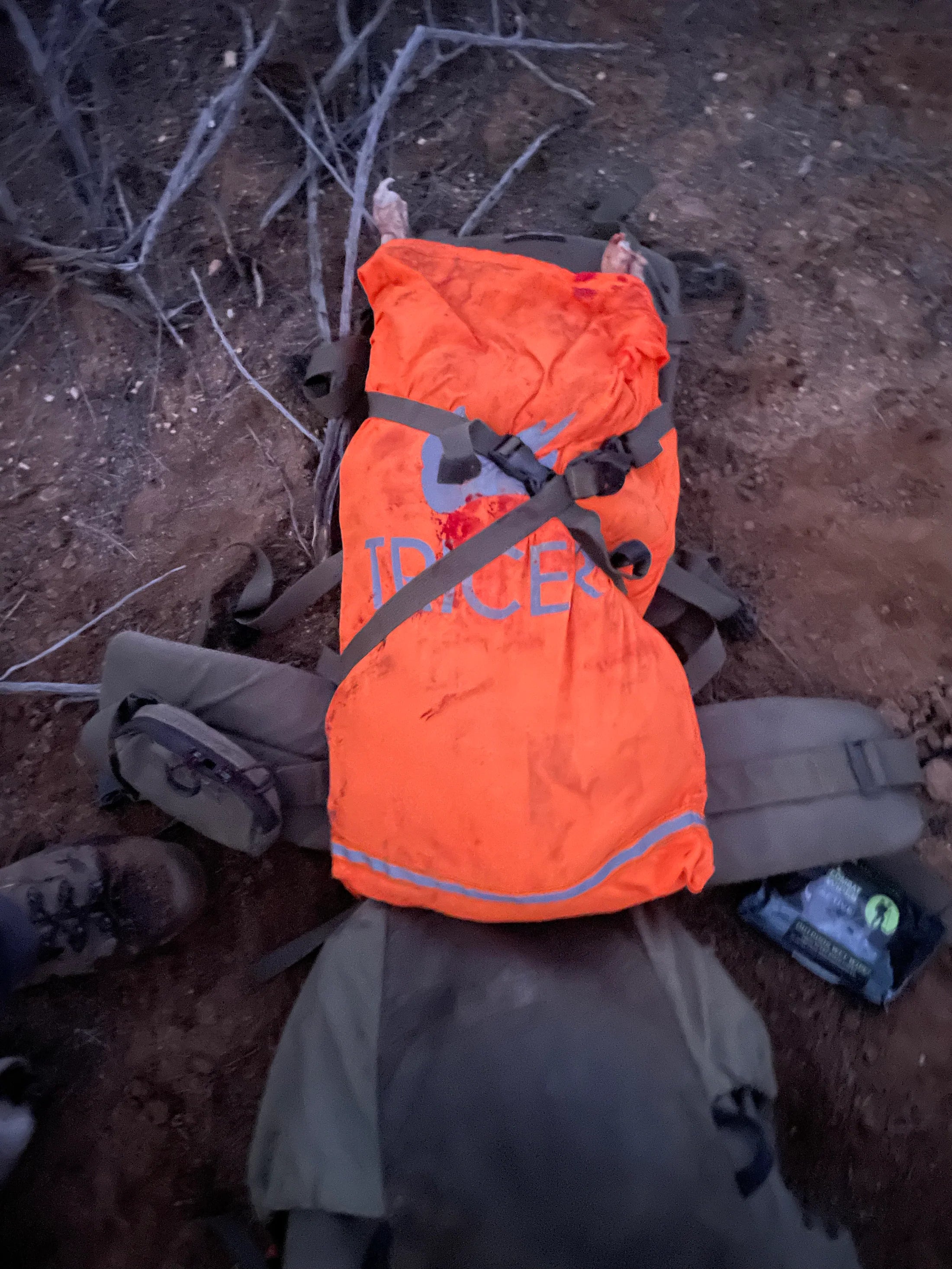Orange game bag with 'TRICER' branding strapped to a backpack
